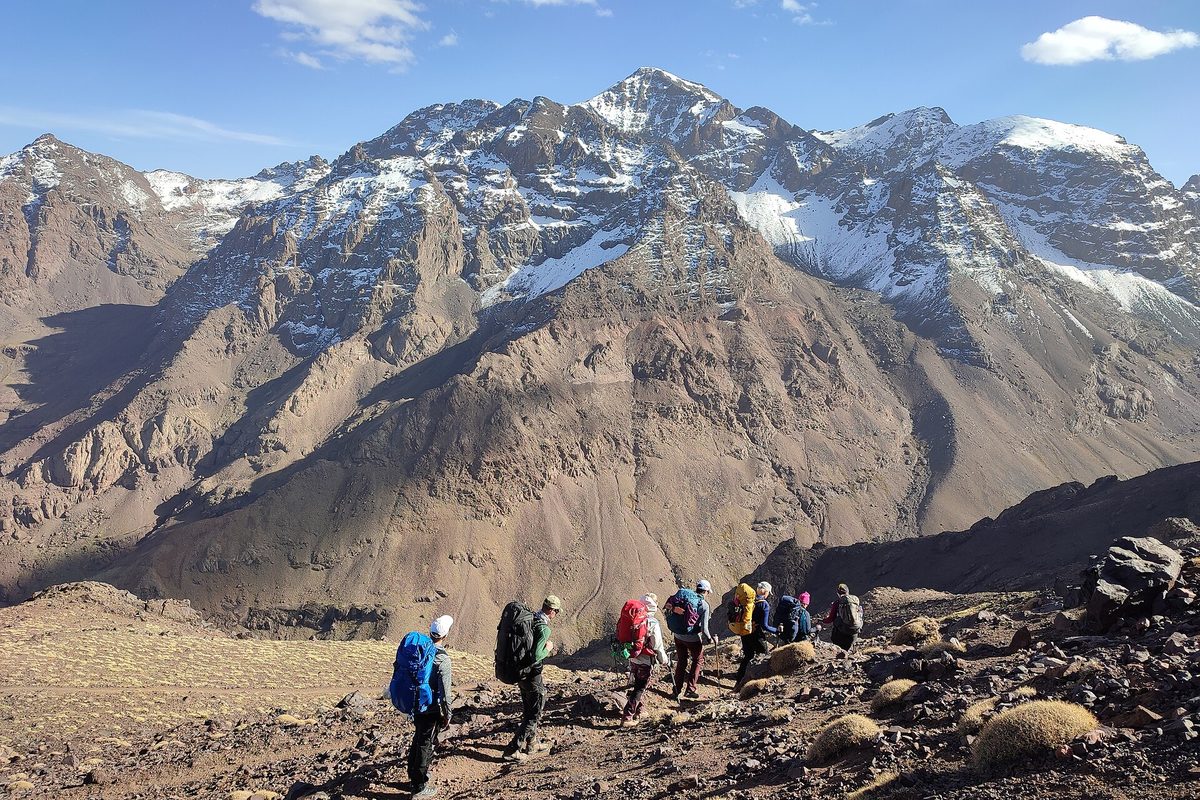 Trekkers beneath the snow-capped Toubkal massif